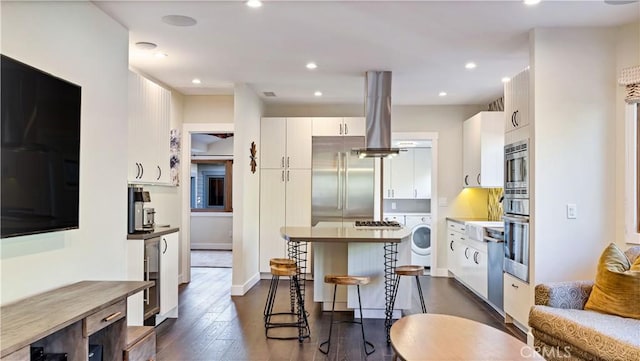 kitchen with island range hood, white cabinetry, a breakfast bar area, dark hardwood / wood-style flooring, and built in appliances