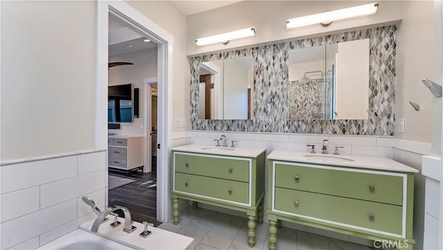 bathroom featuring vanity, a bath, and tile walls