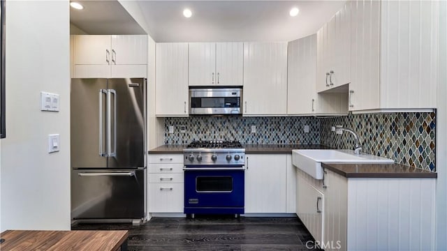 kitchen featuring tasteful backsplash, white cabinetry, sink, and premium appliances