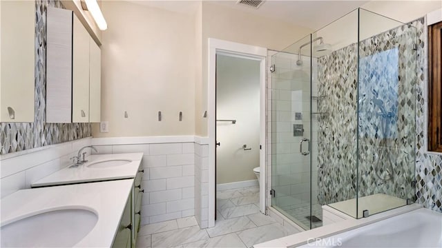 bathroom with vanity, toilet, tile walls, and a shower with shower door