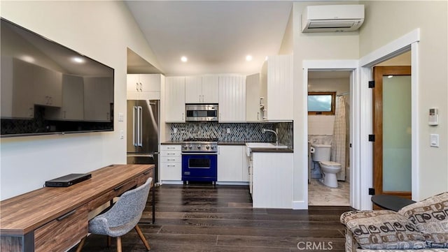 kitchen with lofted ceiling, sink, a wall mounted AC, premium appliances, and white cabinets