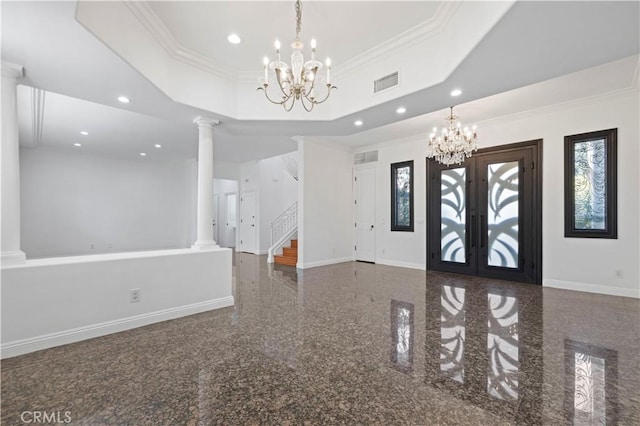 foyer featuring a raised ceiling, ornamental molding, a notable chandelier, and decorative columns