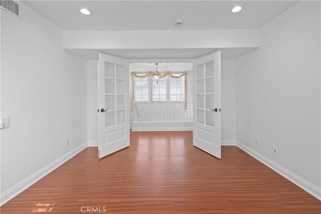 empty room with hardwood / wood-style floors and a chandelier