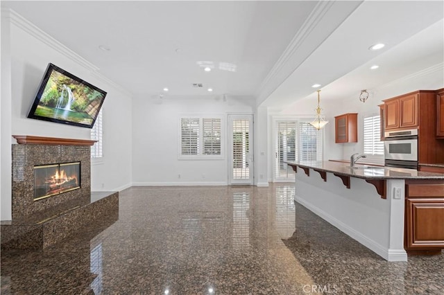 kitchen with double oven, a high end fireplace, ornamental molding, a kitchen bar, and decorative light fixtures