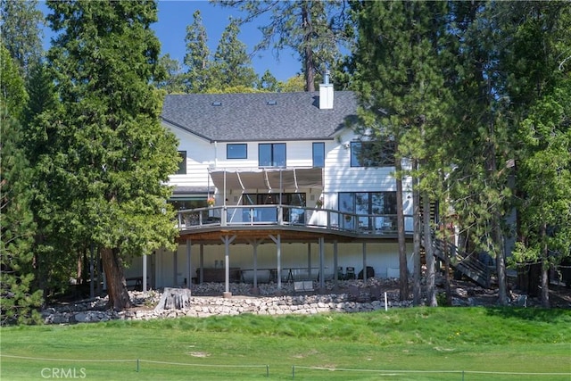 back of property featuring a wooden deck and a lawn