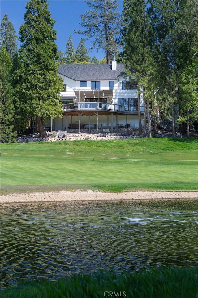 back of property featuring a lawn and a water view