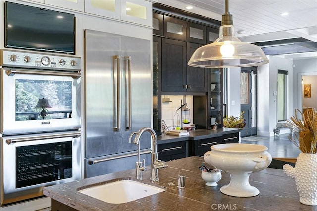 kitchen with dark stone countertops, sink, decorative light fixtures, and appliances with stainless steel finishes