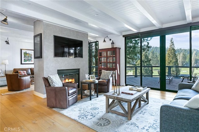 living room featuring hardwood / wood-style floors, a fireplace, and beamed ceiling