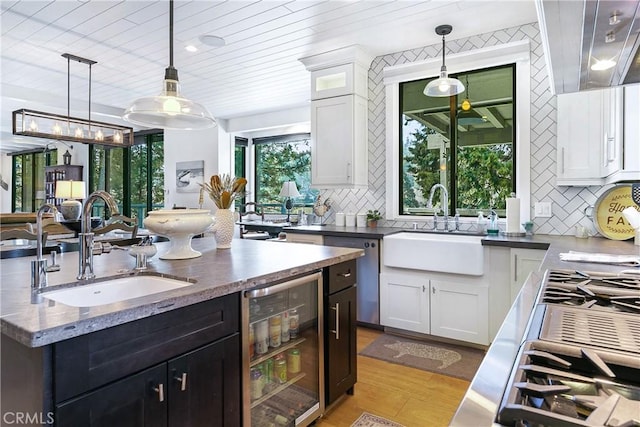 kitchen featuring sink, decorative light fixtures, dishwasher, beverage cooler, and white cabinets