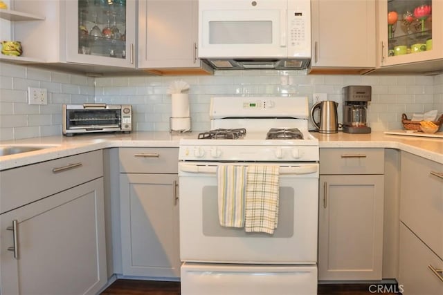 kitchen featuring tasteful backsplash, gray cabinetry, and white appliances