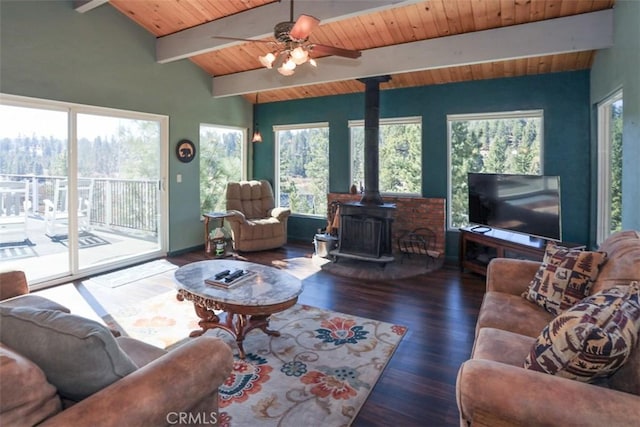 living room featuring dark wood-type flooring, vaulted ceiling with beams, wooden ceiling, a wood stove, and ceiling fan