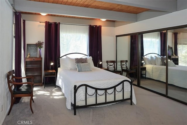 bedroom featuring multiple windows, light carpet, wood ceiling, and beamed ceiling