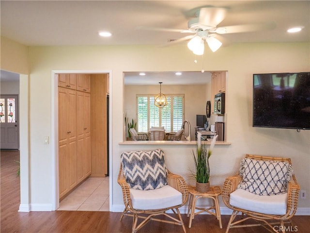 sitting room featuring ceiling fan, sink, and light wood-type flooring