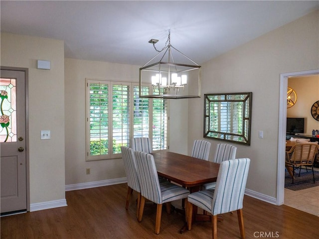 dining space featuring hardwood / wood-style flooring, lofted ceiling, and a notable chandelier