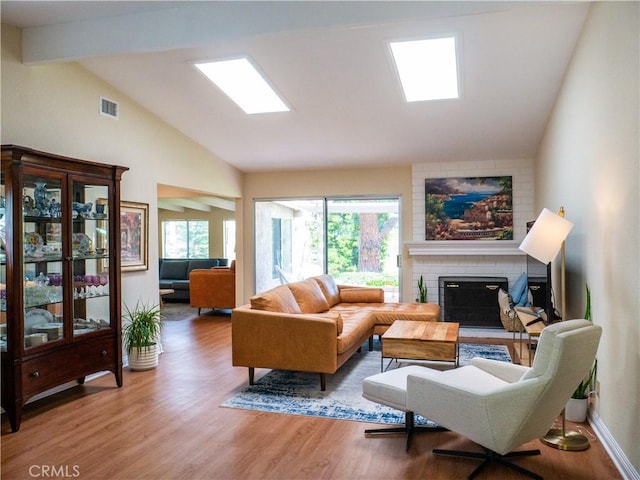 living room featuring a fireplace, lofted ceiling with skylight, and hardwood / wood-style floors