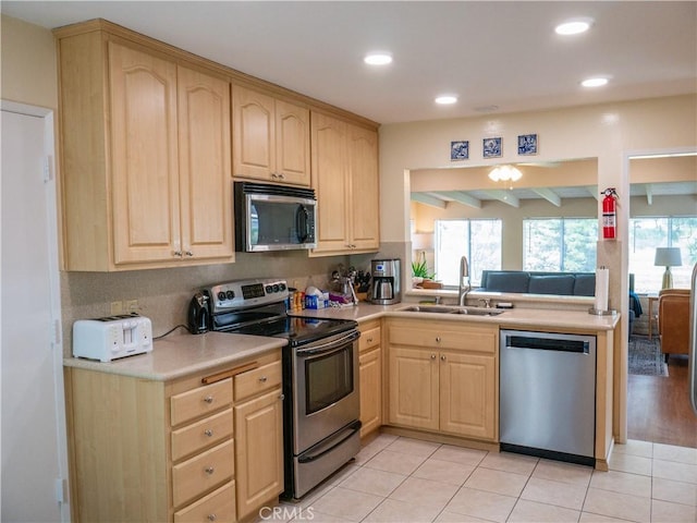 kitchen with sink, light tile patterned floors, appliances with stainless steel finishes, kitchen peninsula, and light brown cabinets