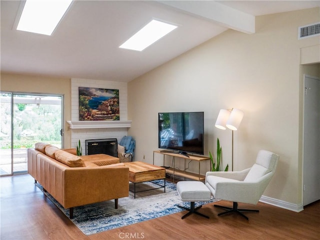 living room featuring a fireplace, wood-type flooring, and lofted ceiling with skylight