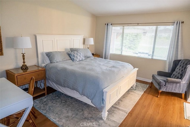 bedroom with vaulted ceiling and light wood-type flooring