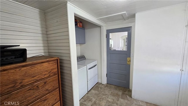 clothes washing area with washing machine and clothes dryer and wooden walls