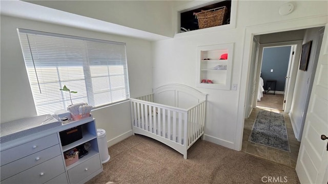 carpeted bedroom featuring a nursery area