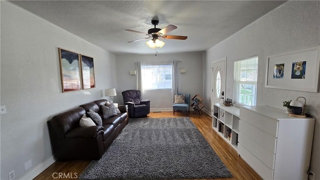 living room featuring dark hardwood / wood-style flooring, ceiling fan, and a textured ceiling