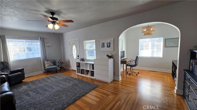 living room featuring ceiling fan, parquet floors, and a textured ceiling