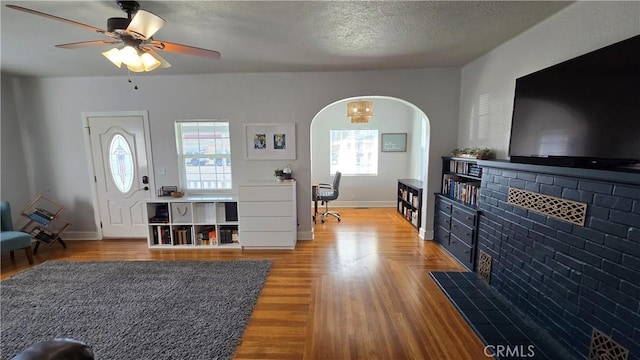 living room featuring hardwood / wood-style flooring, ceiling fan, plenty of natural light, and a textured ceiling