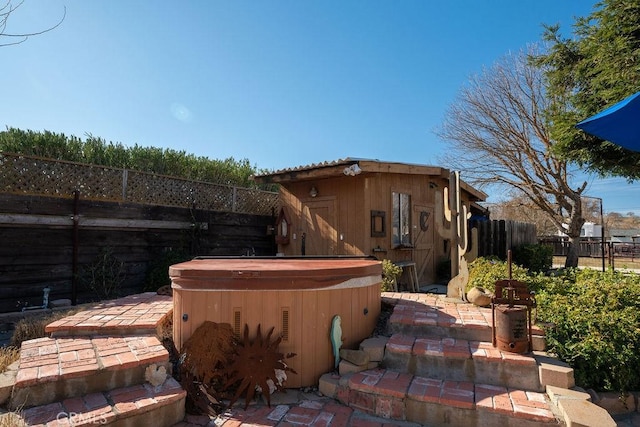 exterior space with a hot tub and a storage unit