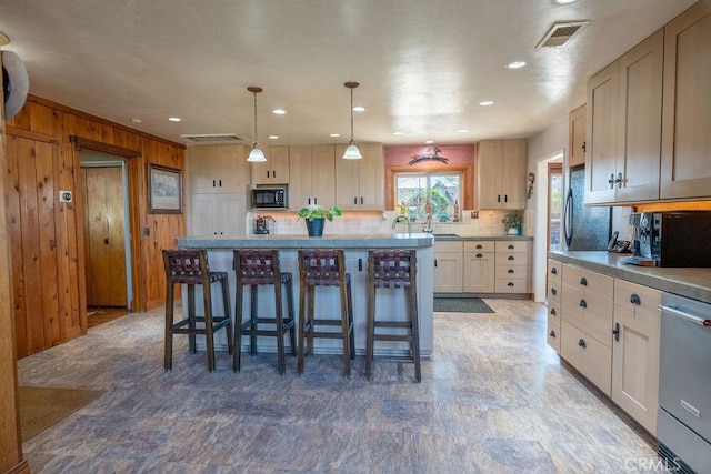 kitchen with pendant lighting, a kitchen bar, a center island, and wood walls