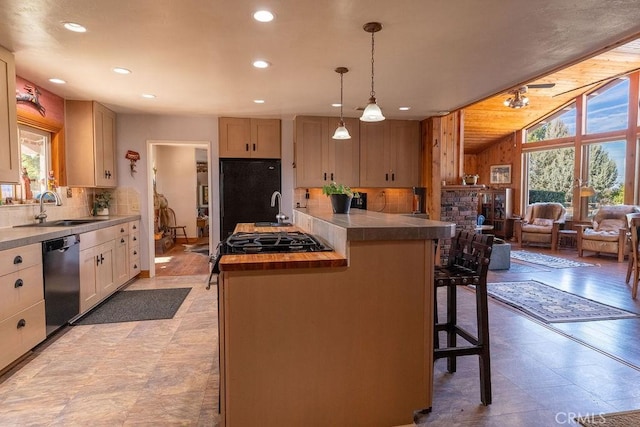 kitchen featuring sink, hanging light fixtures, black appliances, a kitchen bar, and light brown cabinets