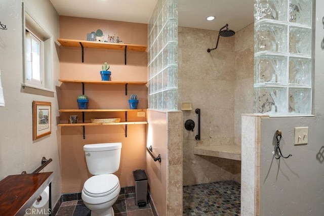 bathroom featuring a tile shower and toilet