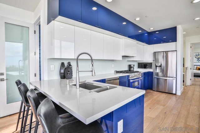 kitchen featuring white cabinetry, sink, a breakfast bar area, stainless steel appliances, and light wood-type flooring