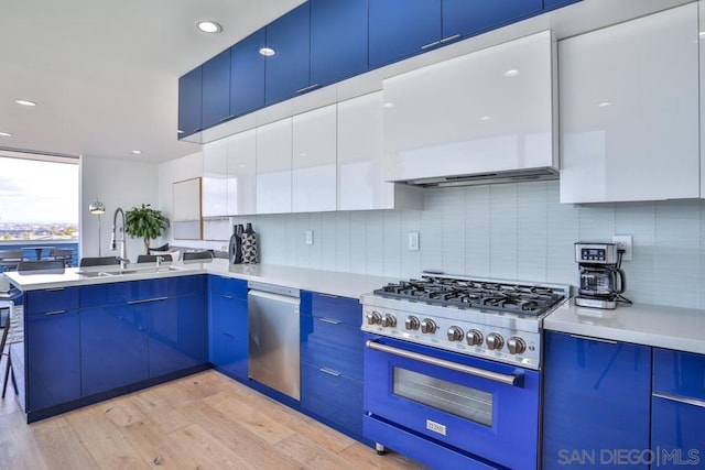 kitchen featuring dishwasher, sink, range, blue cabinetry, and light wood-type flooring