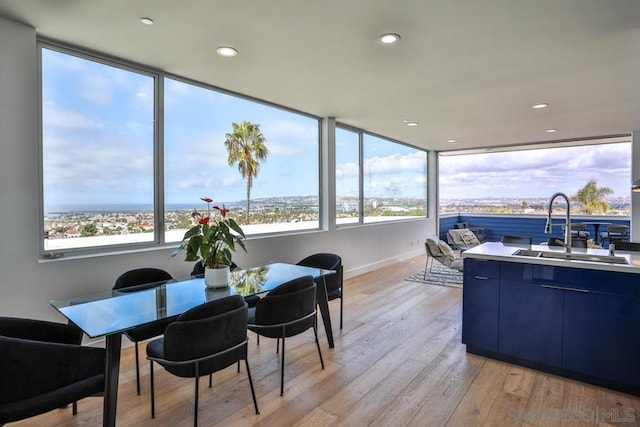 dining space featuring a water view, sink, and light wood-type flooring