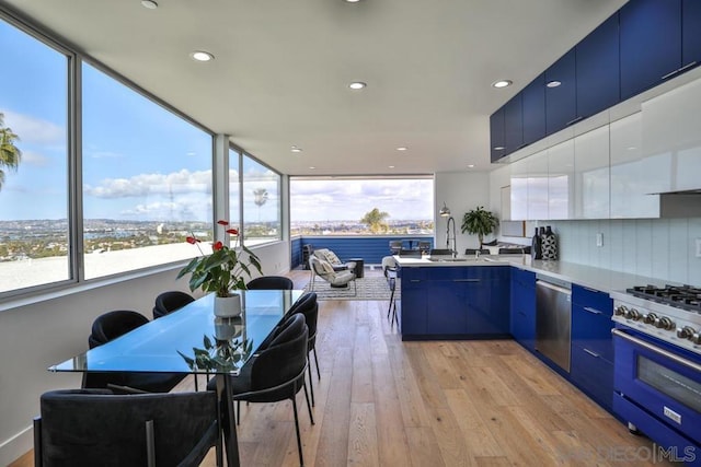 kitchen featuring sink, blue cabinetry, dishwasher, range, and light wood-type flooring