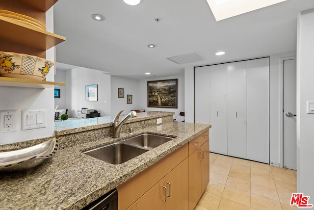 kitchen with light tile patterned flooring, light stone countertops, sink, and light brown cabinetry