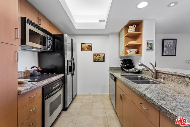 kitchen featuring appliances with stainless steel finishes, light stone countertops, sink, and light tile patterned floors