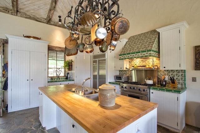 kitchen with an island with sink, premium range hood, white cabinetry, and premium appliances