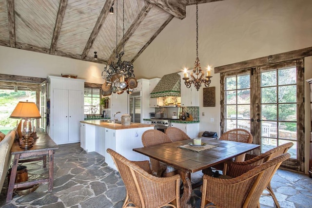 dining room featuring a wealth of natural light, high vaulted ceiling, beam ceiling, and stone tile flooring