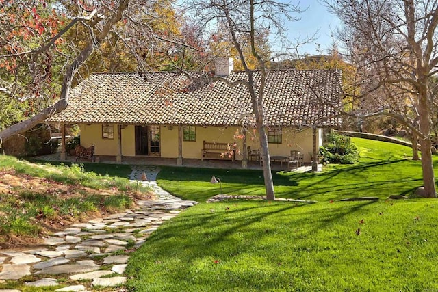 rear view of property featuring a patio, a lawn, and stucco siding