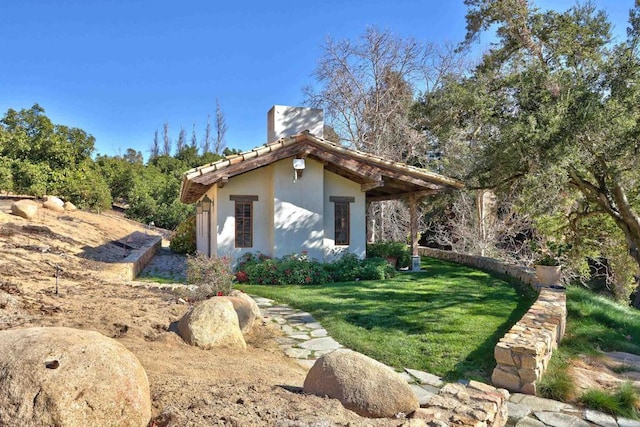 view of property exterior with a yard, a chimney, and stucco siding