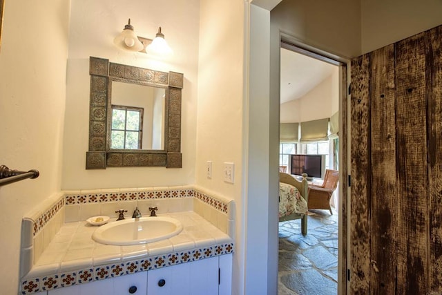 ensuite bathroom featuring stone finish floor, connected bathroom, and vanity