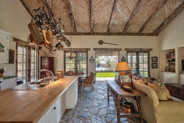 interior space featuring high vaulted ceiling, wooden ceiling, stone tile floors, french doors, and an inviting chandelier