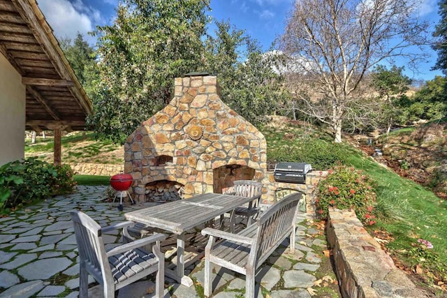 view of patio / terrace with exterior kitchen, an outdoor stone fireplace, a grill, and outdoor dining area