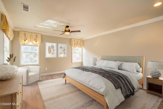 bedroom with hardwood / wood-style flooring, ornamental molding, and multiple windows