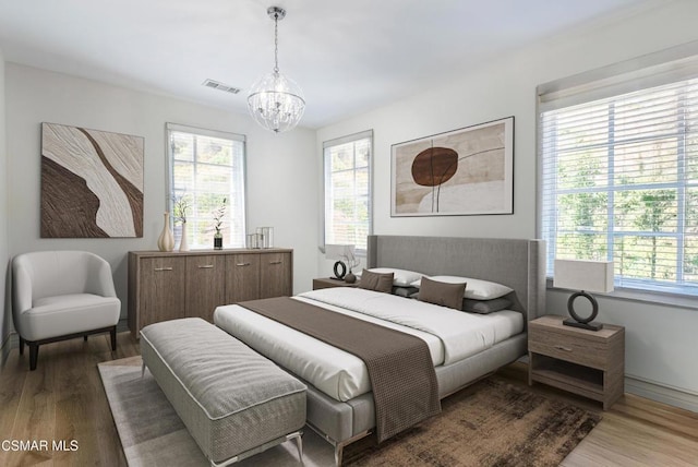 bedroom with multiple windows, hardwood / wood-style floors, and an inviting chandelier