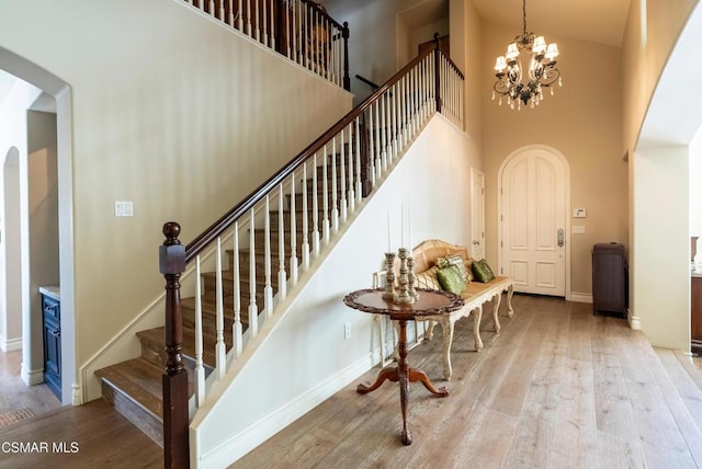 stairs featuring wood-type flooring, a chandelier, and a high ceiling