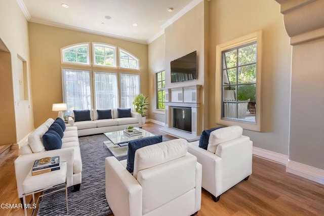 living room with a high ceiling, ornamental molding, and light wood-type flooring