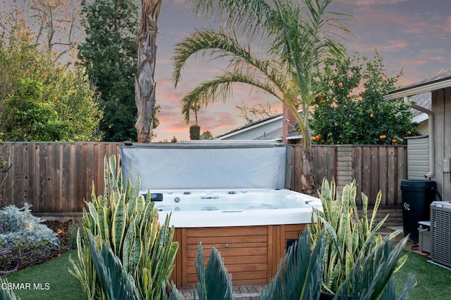 patio terrace at dusk featuring a hot tub