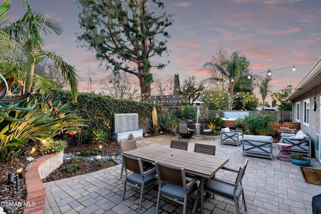 patio terrace at dusk with an outdoor living space and a hot tub